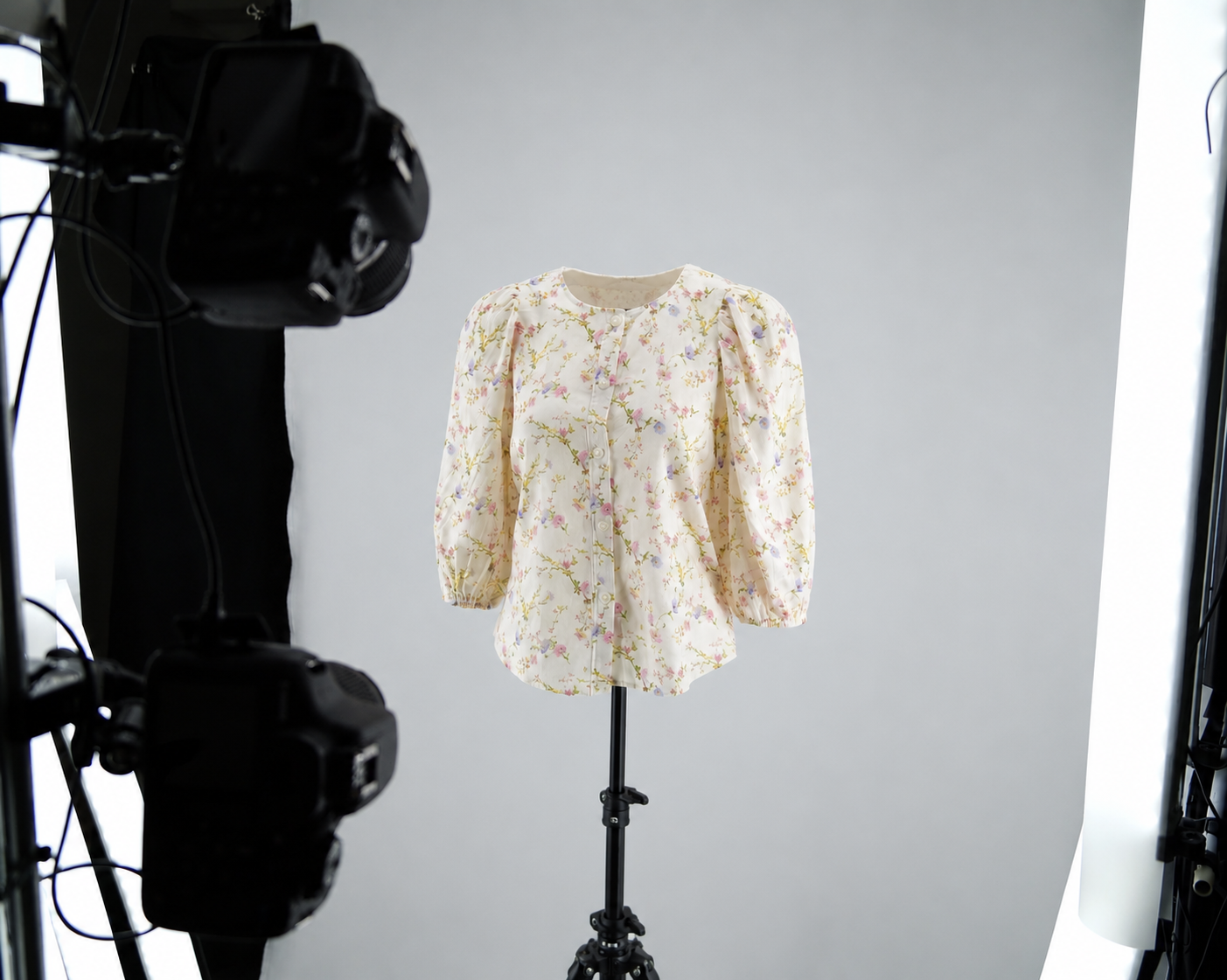 A floral blouse on a mannequin stand inside the Marvify photography rig, lit and framed by a camera for capture.