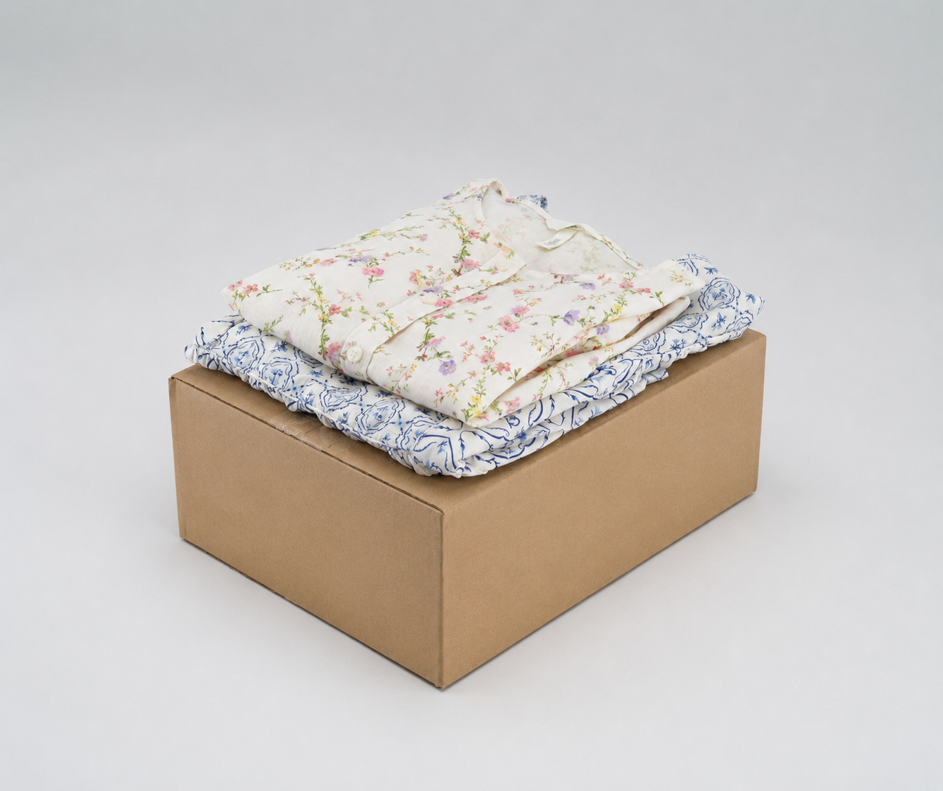 A floral blouse folded on a kraft cardboard shipping box, ready to be sent to the Marvify studio.